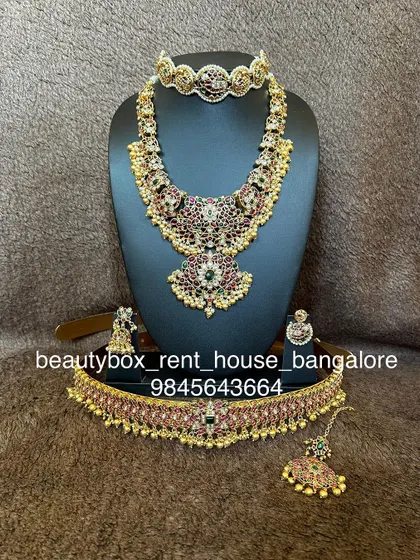 A beautiful guttapusalu-inspired set with ruby and emerald stones, complete with a matching choker, haaram, and vaddanam.