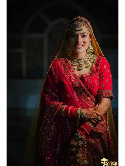 A classic bridal portrait, capturing the bride's happy smile and beautiful green and red lehenga.