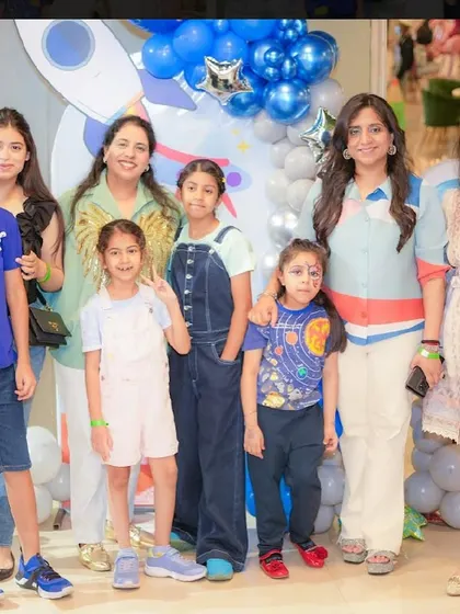A group of kids and adults pose for a photo at a space-themed party.