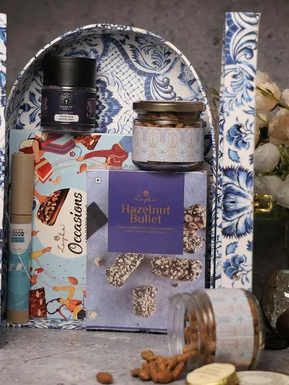 A blue and white patterned arch-box filled with gourmet snacks. This unique shape and design make it a standout gift for Diwali.