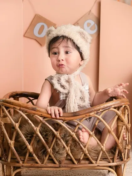 This little one is sitting in a rattan bassinet, dressed as a little bear, creating a super cute and whimsical portrait.