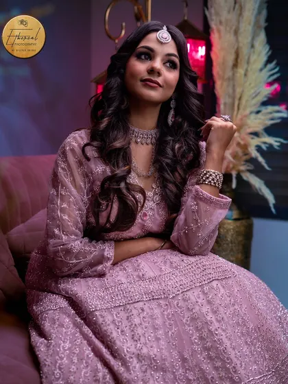 A full-length portrait showcasing an intricately embroidered ethnic gown. The lighting and pose are designed to display the complete look in a sophisticated manner.