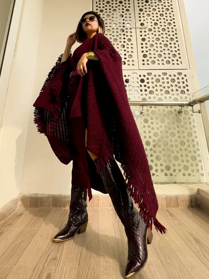 A full-length shot showing the entire silhouette, from the sunglasses to the pointed-toe boots.
