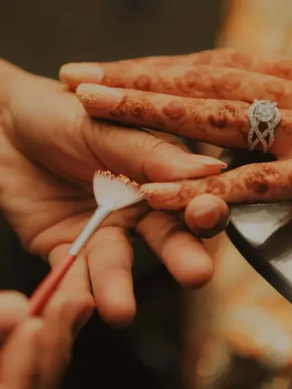 A close-up on the details. This shot captures the final touches being applied to the bride's nails, with her intricate mehendi on display.