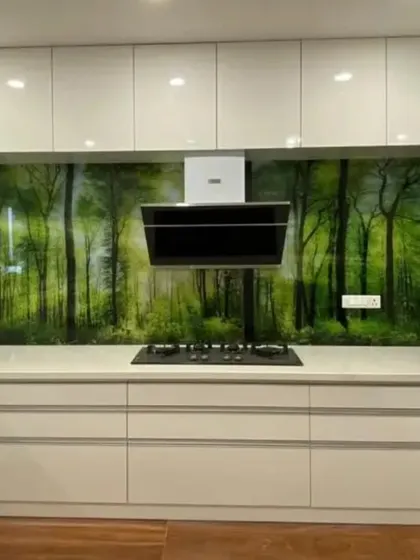 A lush green forest mural installed as a kitchen backsplash, protected by glass. This is a creative and durable way to bring nature into the heart of the home.