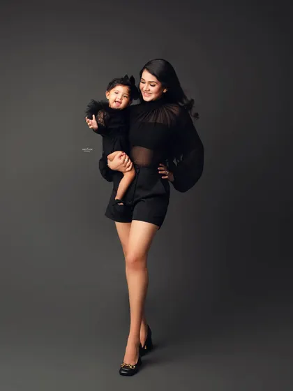 A full-length shot of a mother holding her smiling baby girl, both looking absolutely stunning.