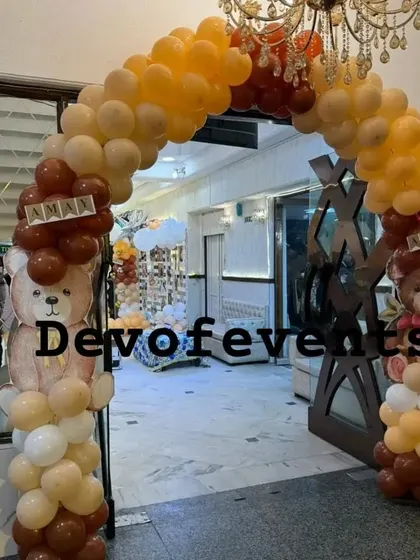 Welcome your guests in style with a themed entrance. This teddy bear balloon arch in shades of brown, beige, and orange creates an inviting entryway for a first birthday party.