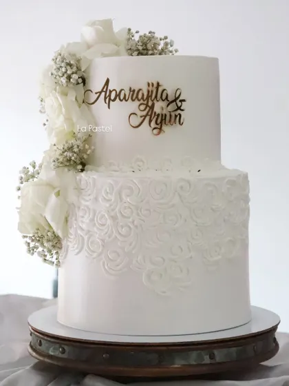 A closer look at the details on this elegant two-tier white cake. The combination of smooth fondant and textured piping creates a beautiful contrast.