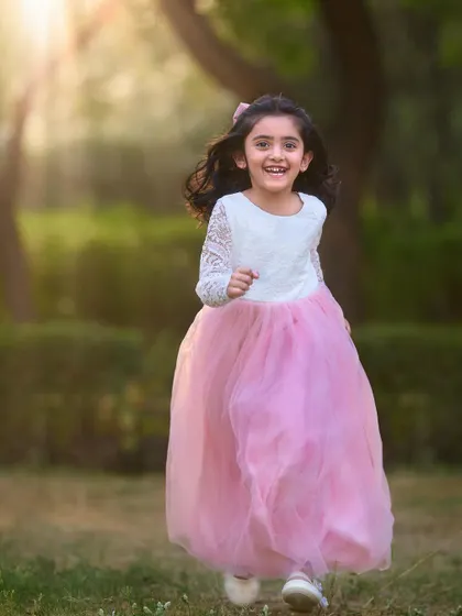 The pure freedom and joy of running through a park. This candid shot of a happy girl in her beautiful pink dress captures the essence of a carefree childhood.