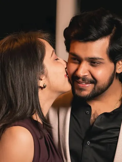 A sweet and spontaneous kiss on the cheek. This candid shot captures a moment of pure affection during their evening photoshoot.
