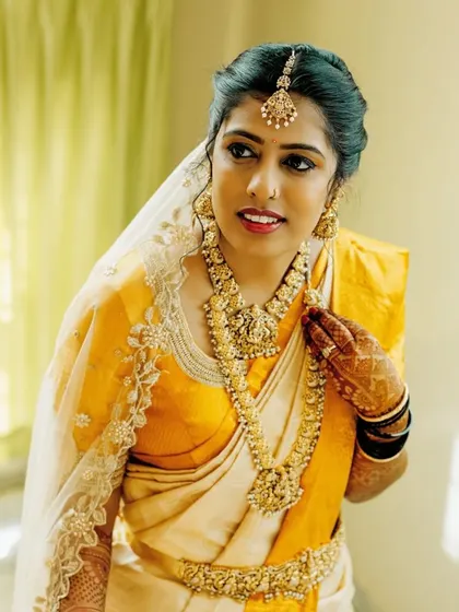 A beautiful close-up of this bride's Muhurtham look. Her makeup features a soft, luminous base with defined eyes, paired with traditional gold jewellery for a classic and timeless appearance.