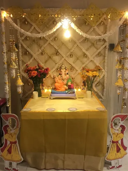 A traditional yellow and white themed mandap with a lattice backdrop and hanging bells. The small cutouts of guards add a unique, classic touch.