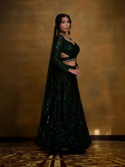 A full-length view of the stunning emerald green sequin lehenga. The complete look, including makeup, hair, and styling, creates a cohesive and breathtaking appearance.