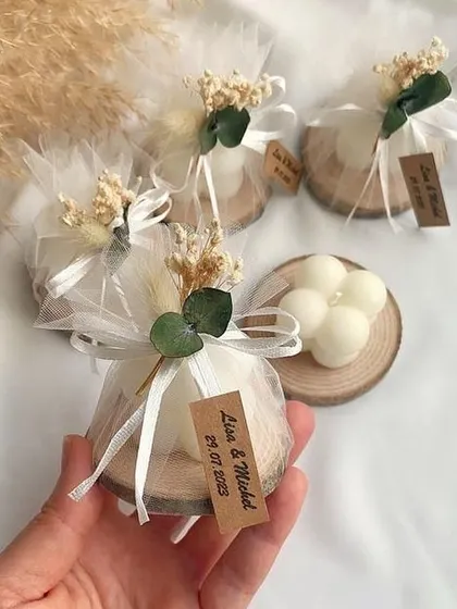 A bubble candle on a wooden coaster, wrapped in a net potli with dried flowers. A beautiful, rustic favor for a wedding.