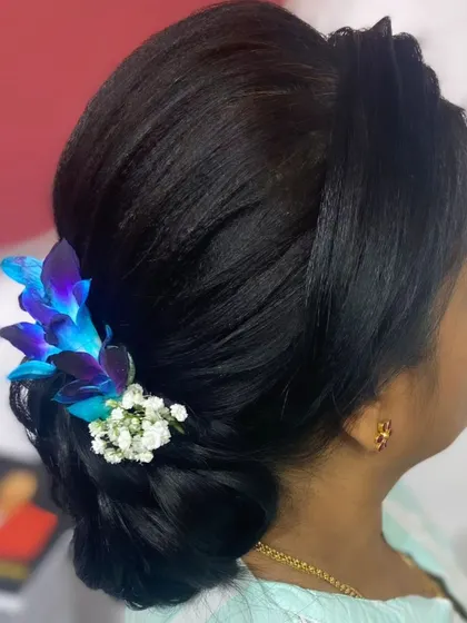 A classic low bun adorned with beautiful fresh blue orchids. This is a sophisticated and elegant hairstyle for any formal occasion.