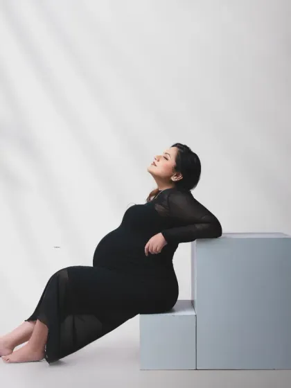 A relaxed and elegant pose. This portrait uses soft, shadowed lighting to create a calm and intimate mood, focusing on the mother's peaceful expression.