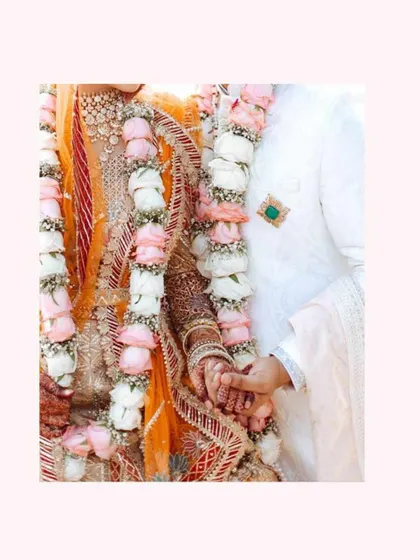 A close-up shot of the bride and groom's hands and their exquisite floral garlands, showcasing the intricate design and fresh flowers.