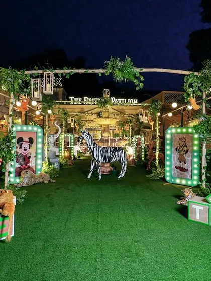 The outdoor safari setup at night, with illuminated character frames, large animal props, and letter blocks for the birthday boys' ages.