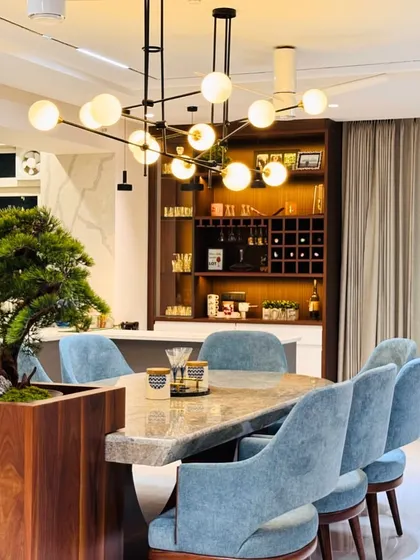 This dining area features a unique table with a live bonsai tree integrated into its design, bringing a touch of nature indoors. The light blue chairs add a soft touch of color.
