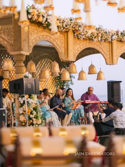 Music and tradition come together in this beautiful setting. The mandap, adorned with temple bells and intricate carvings, provides a stunning backdrop for the live musicians performing during the ceremony.
