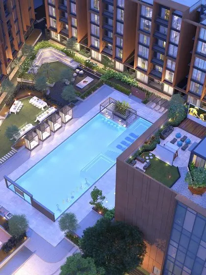 An aerial night view of Casagrand SouthBrooke's central courtyard, showing the illuminated pool and rooftop terrace as glowing hubs of evening activity.