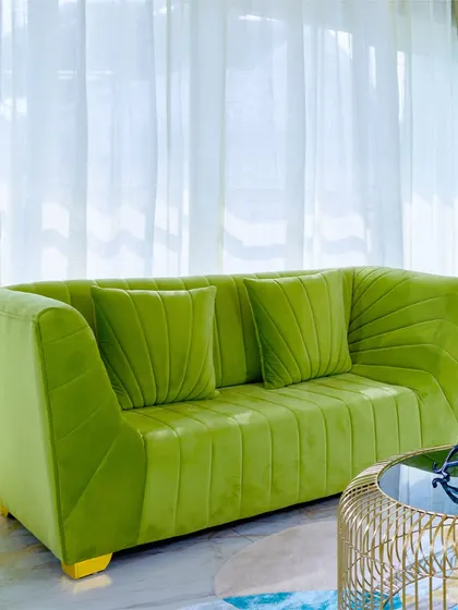A close-up of the stylish green sofa, showing the detailed pleating and comfortable design.