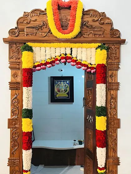 This beautiful pooja door is decorated with fresh flower garlands, showing how these traditional entrances become a living part of family rituals and celebrations.