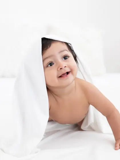 Peek-a-boo from under the covers! A playful and sweet moment from a sitter session, full of smiles.