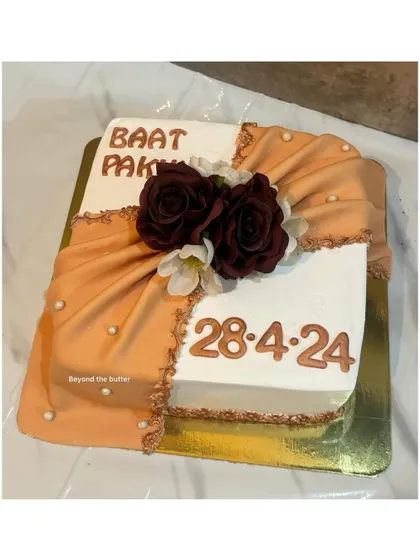 This "Baat Pakki" cake features a beautiful fondant drape effect, reminiscent of a traditional outfit. The design is completed with deep red roses and the special date to mark the occasion.