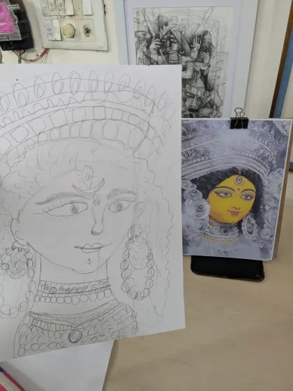 This image shows the process of learning to draw from a reference. On the right is the reference photo of Durga, and on the left is a student's pencil sketch, capturing the facial features and ornaments.