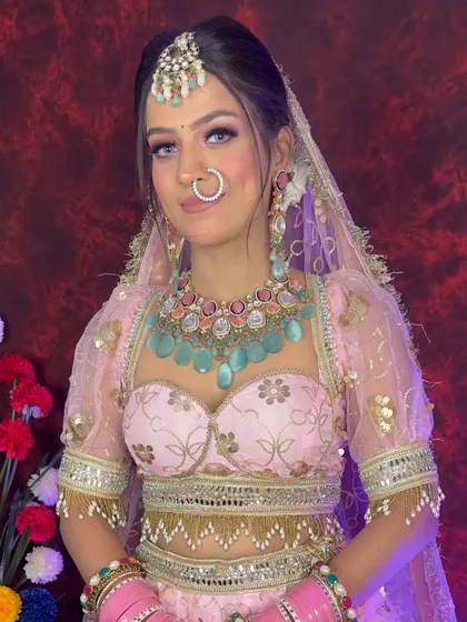 A bride in a baby pink lehenga with a pastel blue Kundan necklace. This soft, colorful look is ideal for a summer or daytime wedding ceremony.