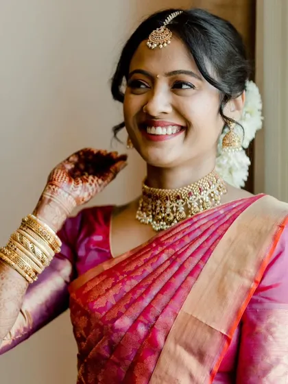 A close-up of this South Indian bride's joyful expression. The makeup is kept soft and elegant, with a classic red lip and a simple bindi to complete the traditional look.