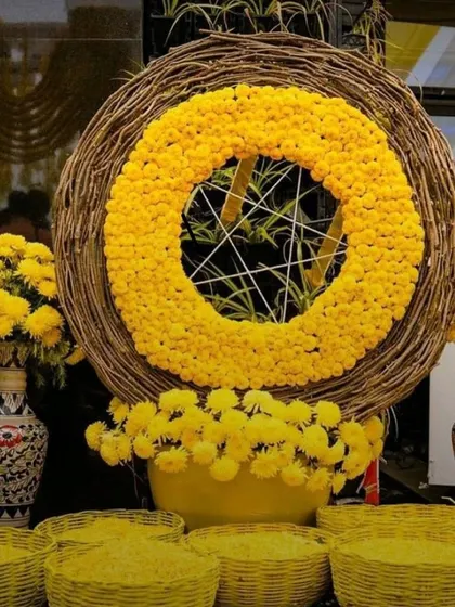 This unique Haldi decor piece features a large ring made of woven twigs, centered with a dense circle of yellow marigolds. It serves as a modern and rustic focal point for the event.