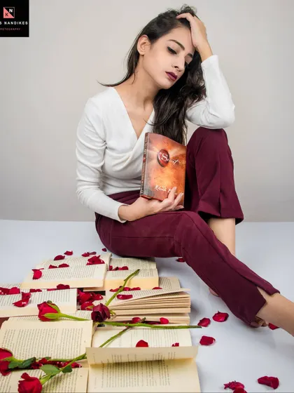 A different angle from the 'Bittersweet Memories' series. The model's pose, with her head in her hand, conveys a sense of melancholy and heartbreak amidst the romantic props of books and roses.
