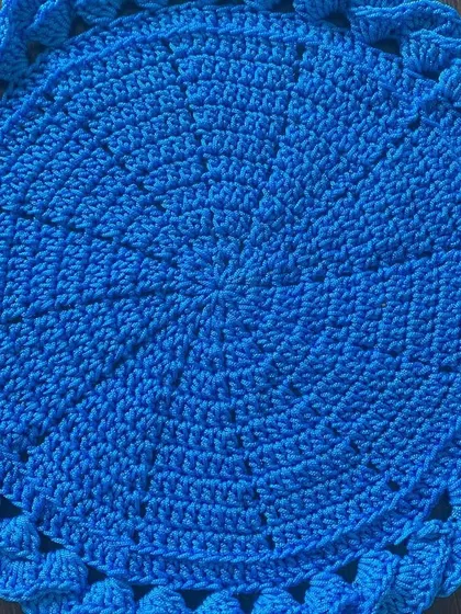 This vibrant blue placemat has a unique braided or woven border, giving it a lot of texture and visual interest.