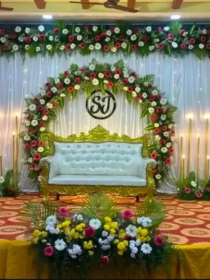 A colorful engagement stage with a semi-circular floral arch, a custom monogram, and bright flower arrangements.