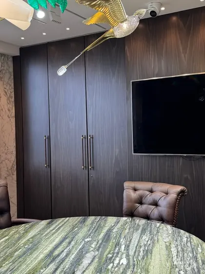 Functionality meets style with these dark wood-paneled cabinets, providing ample storage while seamlessly integrating a large screen for presentations in the conference room.