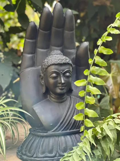 Our black marble Buddha in a blessing hand sculpture, seen here nestled among ferns, adds a touch of serenity and botanical styling to any corner.