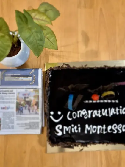 A celebration cake next to the newspaper article announcing our award. We celebrate these milestones with our wonderful team and students.