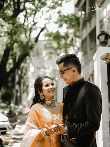A candid shot of a couple sharing a sweet moment while walking down a tree-lined street.