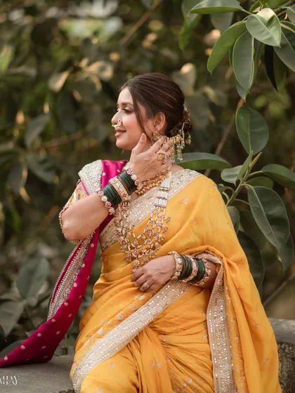 A moment of quiet reflection. The side profile showcases the elegant updo and the way the makeup enhances her features without overpowering them. The yellow saree glows in the natural light.