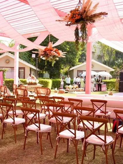 The guest seating area for the rustic Mehendi, with cross-back chairs and pink drapes creating a relaxed yet elegant outdoor lounge.