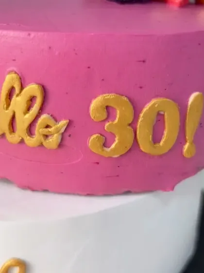 A close-up of the hand-piped golden message on the "Hello 30" cake.