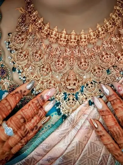 A detailed shot focusing on the bride's magnificent temple jewellery necklace and henna-covered hands. I take care to capture these important details that complete the bridal look, showcasing the craftsmanship and cultural significance.