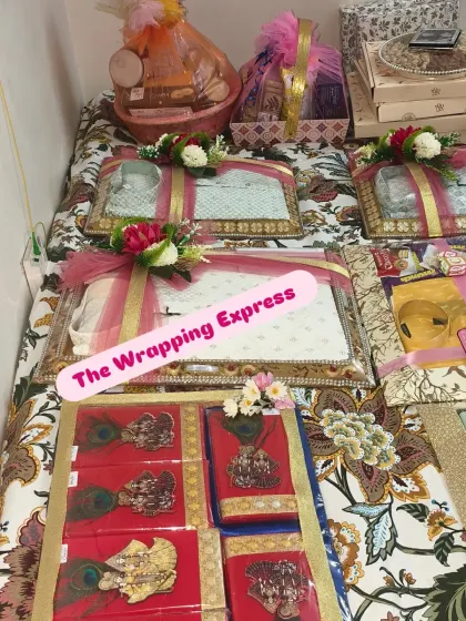 An overview of a large trousseau packing project for a baby girl, with multiple trays of clothes, baskets, and other gifts.