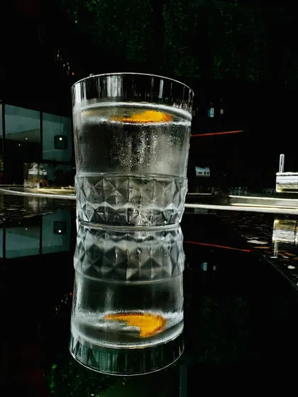 A refreshing cocktail in a crystal glass, reflecting on a dark, glossy surface.