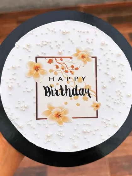 An elegant birthday cake with an edible floral print and delicate pearl sprinkles.