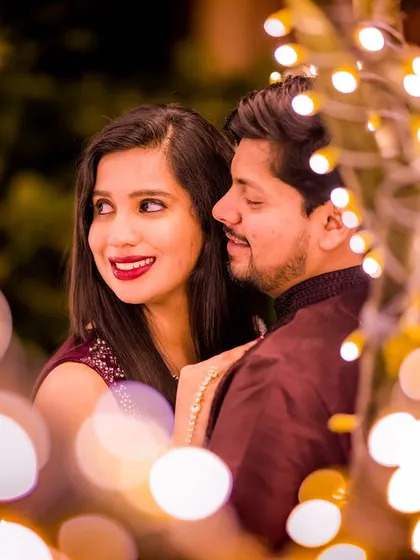 A close-up shot capturing the couple's happy expressions, framed by the soft, warm blur of fairy lights. It’s a perfect example of a candid romantic photo.