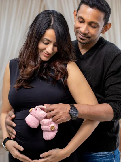 Holding the tiny pink baby shoes against the bump is a sweet and hopeful gesture, beautifully captured in our studio.