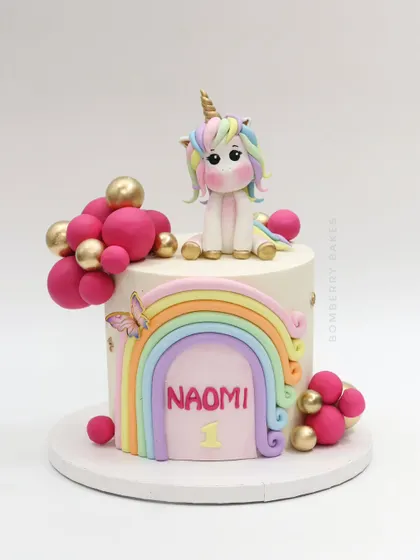 The full view of the pastel rainbow and unicorn cake, decorated with a cute fondant unicorn, a rainbow, and pink and gold spheres.